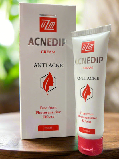 Acnedip anti-acne cream packaging with tube and box on a wooden surface.