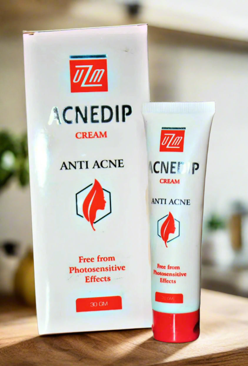 Two tubes of Acnedip anti-acne cream on a wooden surface with a blurred background.